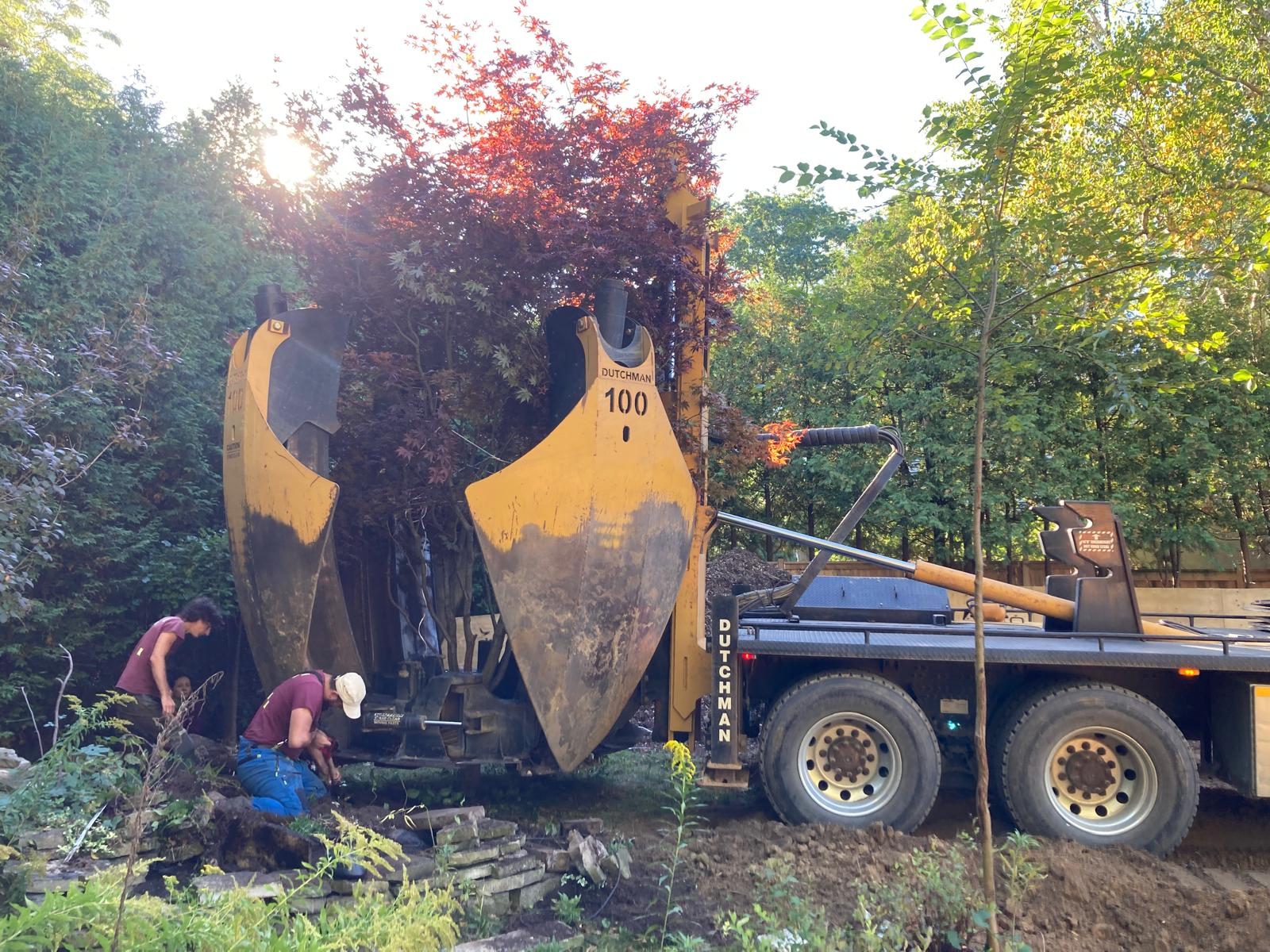 Truck-mounted tree spade lifting a root ball on a Durham Region property